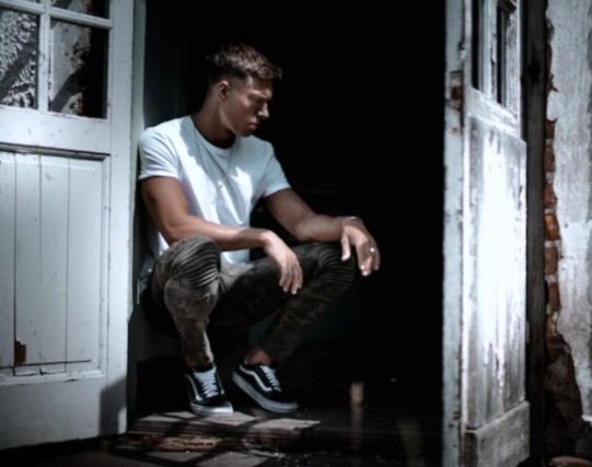 dark broody man crouching at a doorway