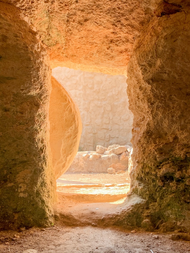 Light streaming out of an empty stone tomb with the stone rolled away