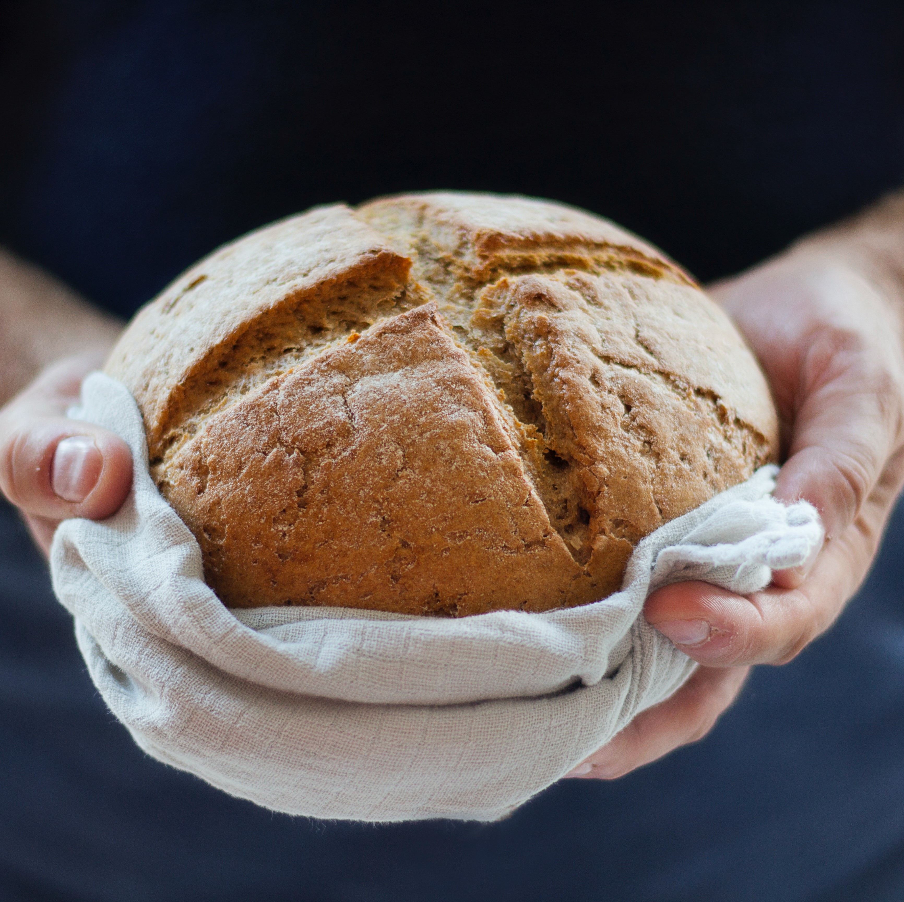 hands holding single loaf of bread